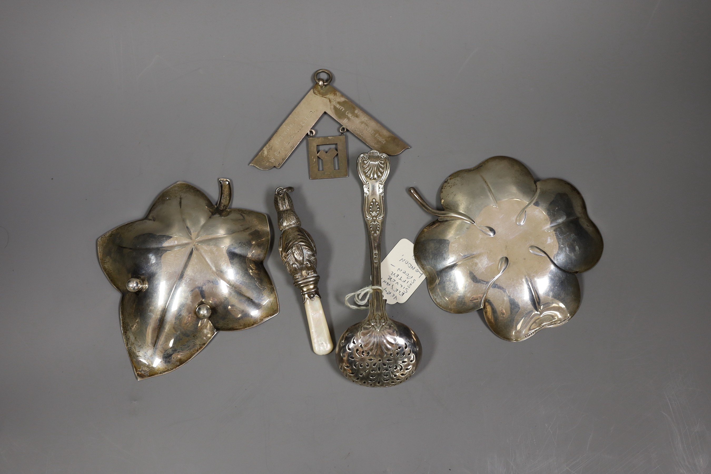 Two Tiffany & Co sterling leaf dishes, largest 14.6cm and three other items including a child's silver rattle, silver masonic jewel and a late Victorian silver sifter spoon.
